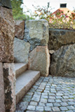 Stenmur i natursten och stenplan i gatsten